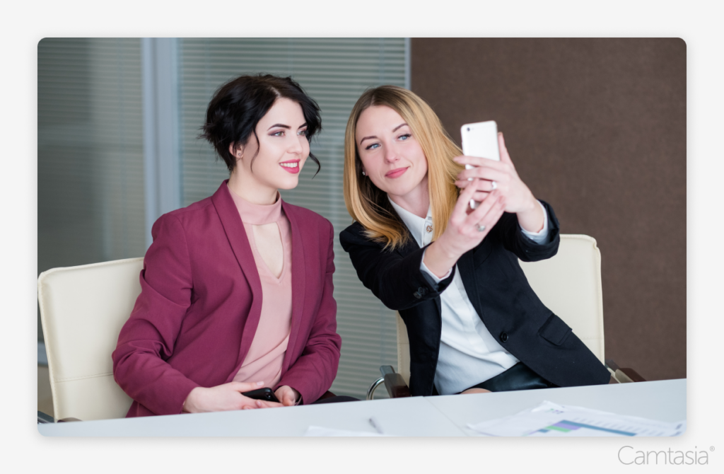 Two businesswomen taking a selfie on a phone.