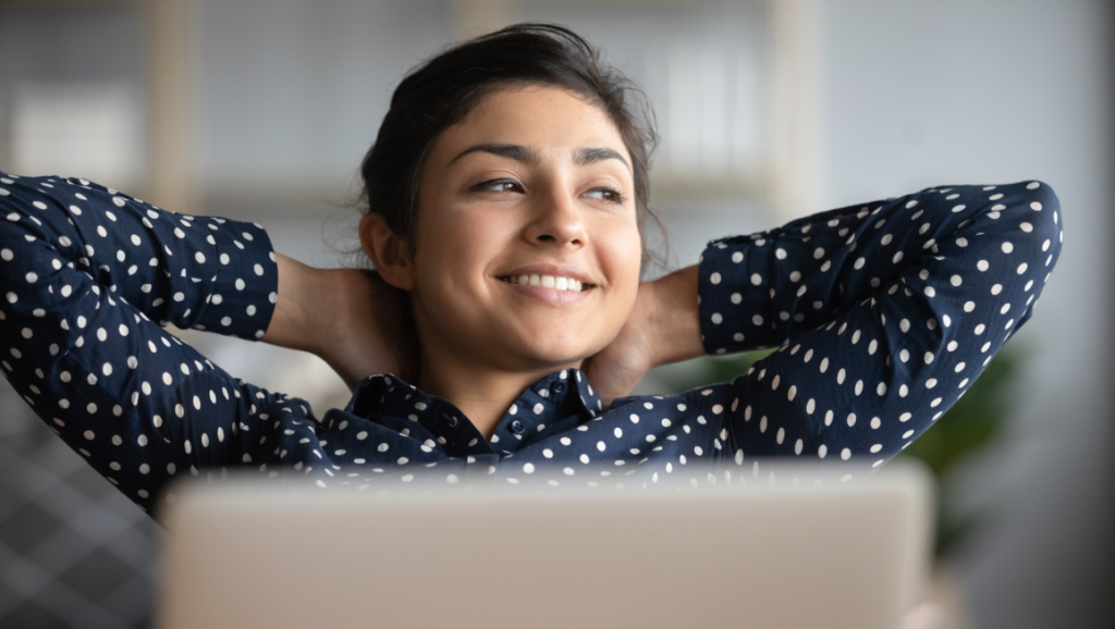 A young businesswoman leaning back from her laptop and smiling.