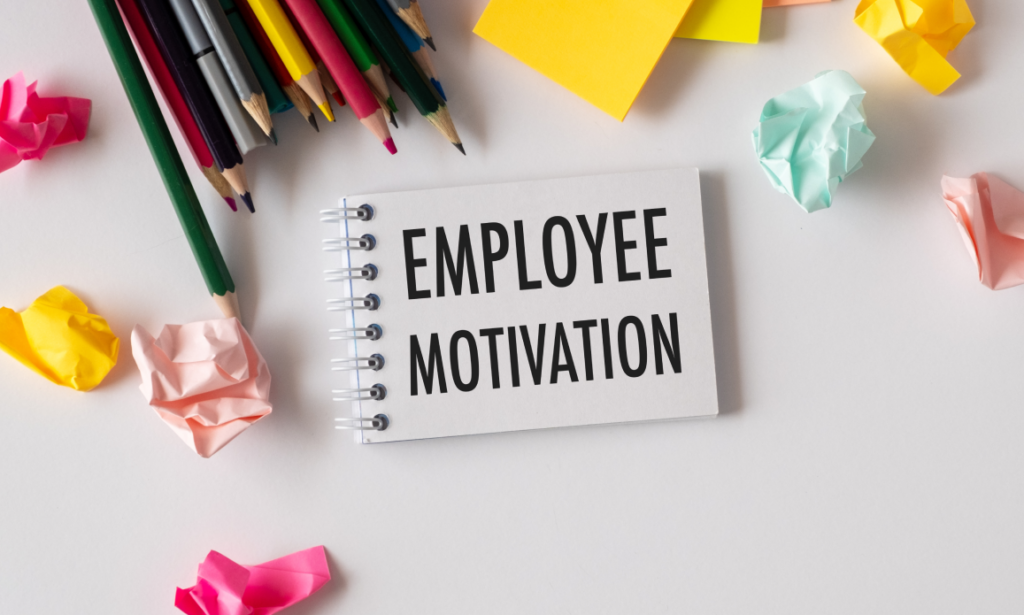 A notebook entitled 'Employee Motivation' surrounded by colorful paper and pencils.