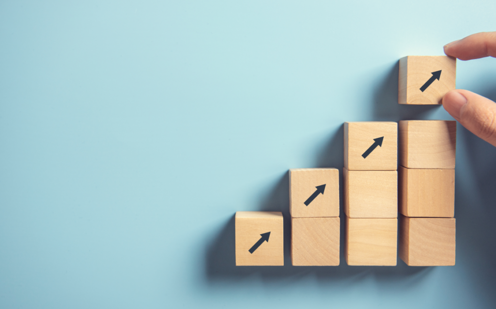 Stacked wooden blocks with arrows pointing up and to the right indicating growth.